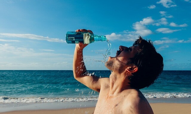 Mężczyzna pijący wodę na plaży