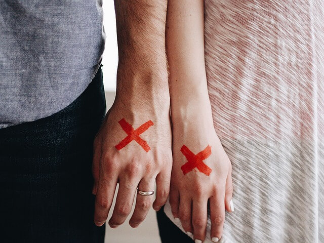 Czerwone krzyżyki na dłoniach małżonków