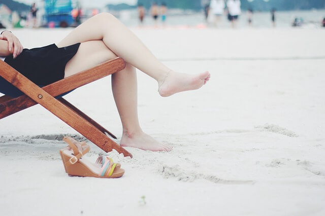 Kobieta na plaży ze złym nawykiem zakładania nogi na nogę