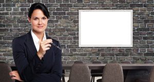Czym różni się lider od managera Pewna siebie liderka stoi ze skrzyżowanymi rękami przed salą konferencyjną z pustą tablicą