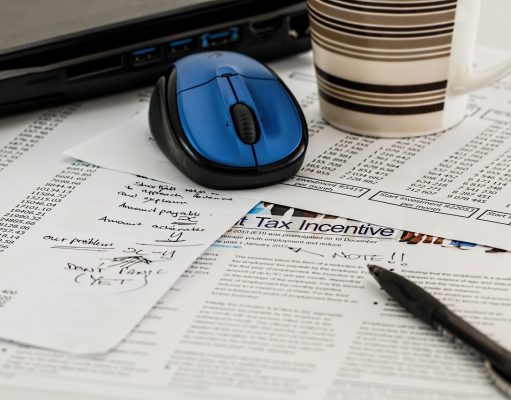 Dokumenty podatkowe z napisem Tax Incentive, długopis, mysz komputerowa i kubek kawy na biurku.