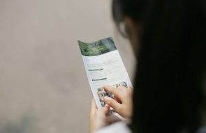Broszura, czyli jak dobrze wypowiedzieć się o firmie, produkcie na papierze? Kobieta przegląda broszurę